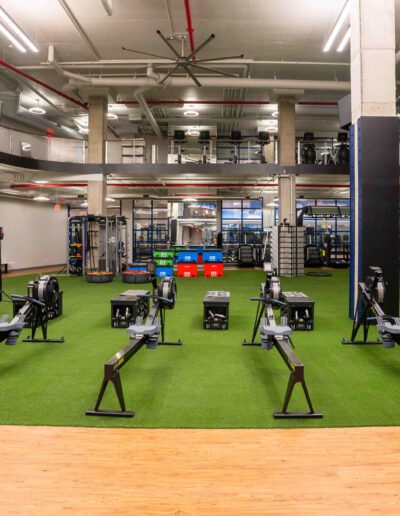 A gym with a row of rowing machines on the floor.